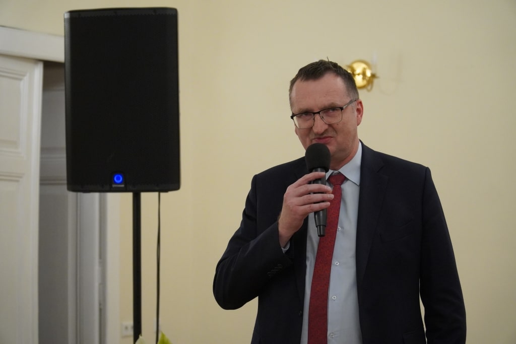 Mężczyzna w garniturze przemawia na inauguracji roku akademickiego Akademii Trzeciego Wieku