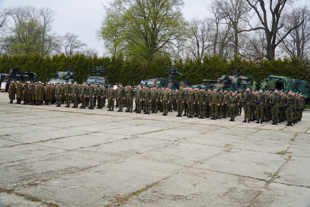 Żołnierze 21. Dywizjonu Artylerii Przeciwlotniczej na placu apelowym z pojazdami wojskowymi