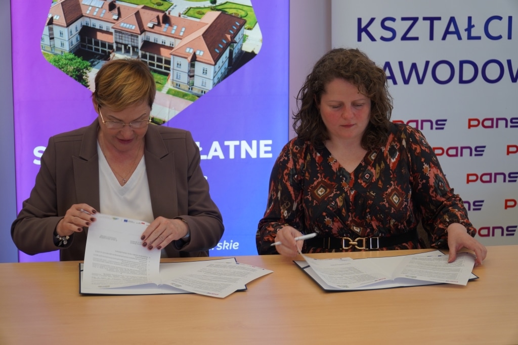 Dwie kobiety podpisują dokumenty na konferencji „Poprawa jakości kształcenia osób dorosłych”