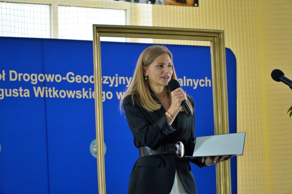 Kobieta z mikrofonem i laptopem na jubileuszu Zespołu Szkół Drogowo-Geodezyjnych w Jarosławiu