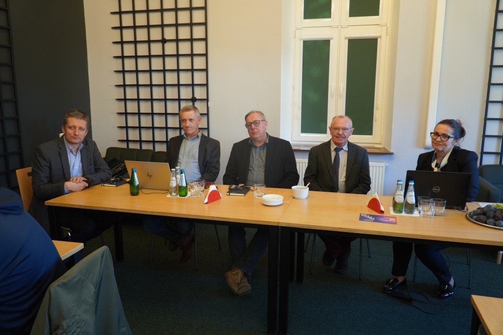 Pięciu uczestników konferencji RIPE w Jarosławiu siedzi przy stole.