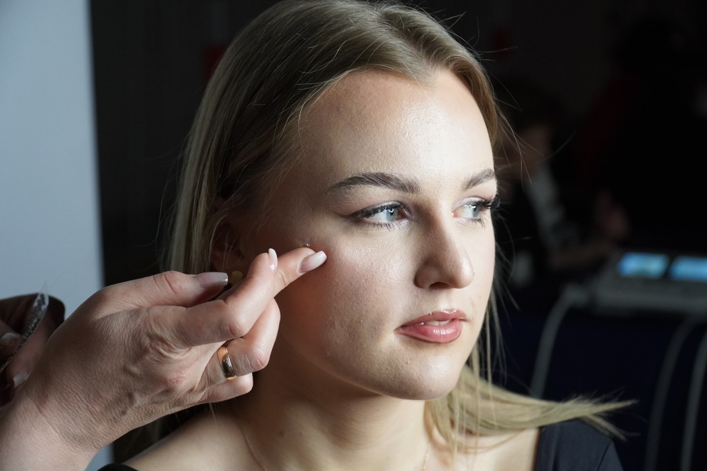 Makijażystka poprawia makijaż blondynce podczas Gminnego Dnia Kobiet w Zarzeczu.