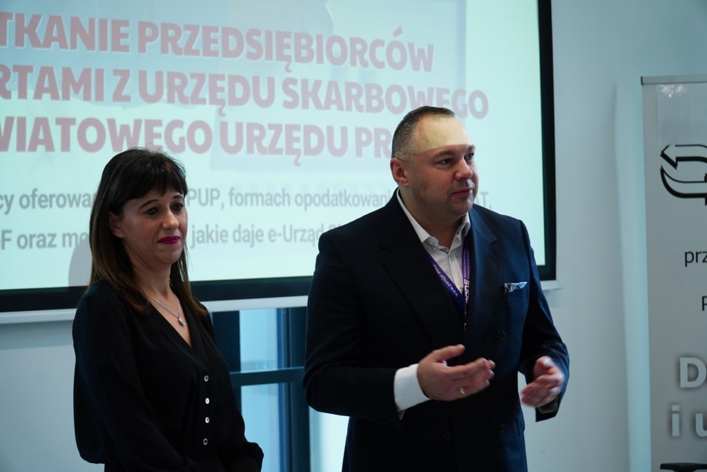 Spotkanie przedsiębiorców: mężczyzna i kobieta przed ekranem z tekstem