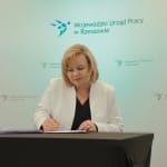 Kobieta podpisuje dokumenty w Wojewódzkim Urzędzie Pracy w Rzeszowie.