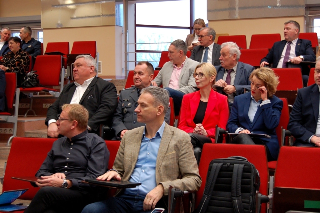 Uczestnicy Ogólnopolskiej Konferencji Naukowej Bezpieczeństwo Informacyjne w Zarządzaniu Kryzysowym siedzą w sali.