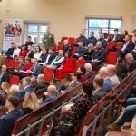 Uczestnicy konferencji naukowej Bezpieczeństwo Informacyjne w Zarządzaniu Kryzysowym siedzą na sali.