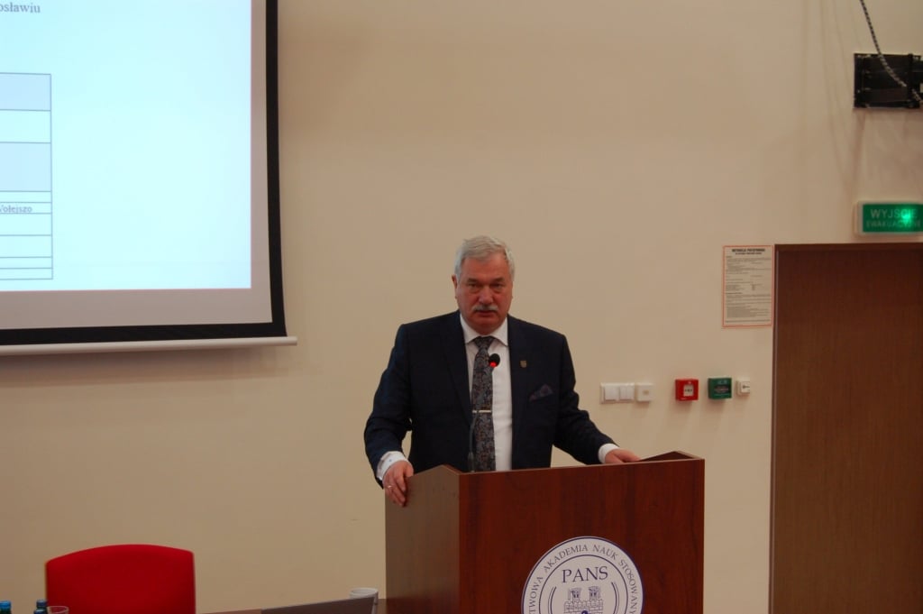 Mężczyzna w garniturze przemawia przy mównicy podczas konferencji naukowej