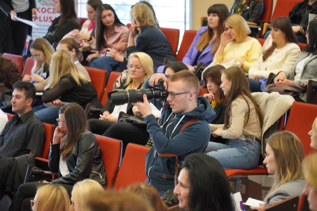 Konferencja naukowa WH: Uczestnicy słuchają wykładu, kobieta robi zdjęcie