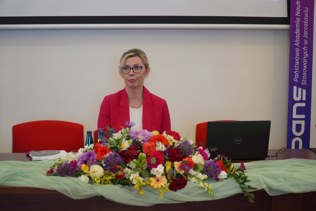 Konferencja naukowa WH: Kobieta w okularach przy stole z kwiatami