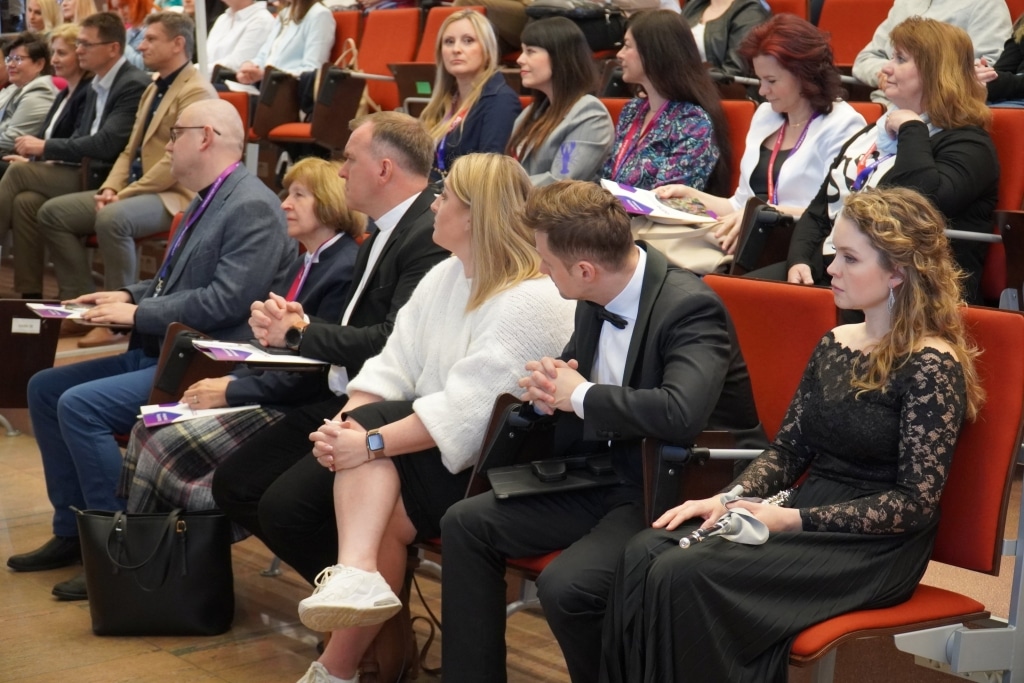 Uczestnicy konferencji naukowej WH siedzą w sali, słuchając prelegentów.