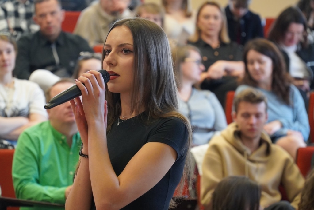 Młoda kobieta przemawia na konferencji naukowej WH o bólu duszy