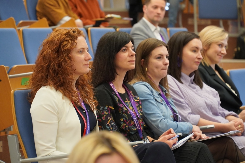 Uczestniczki konferencji naukowej WH siedzą w rzędzie, słuchając prelekcji.