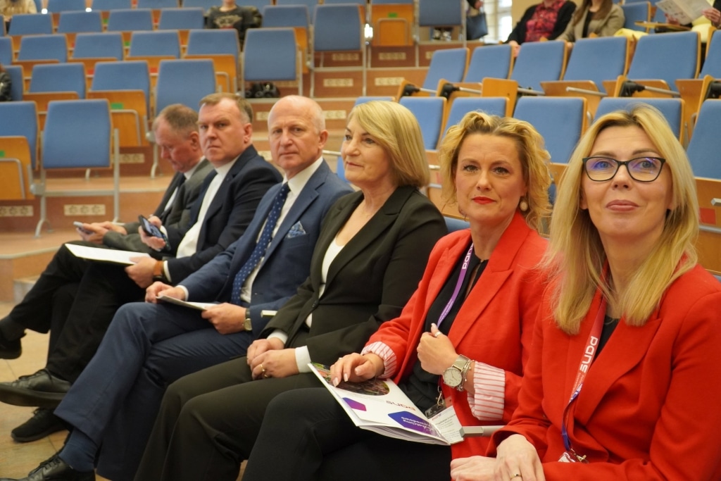 Uczestnicy konferencji naukowej WH siedzą w rzędach, słuchając prelegentów