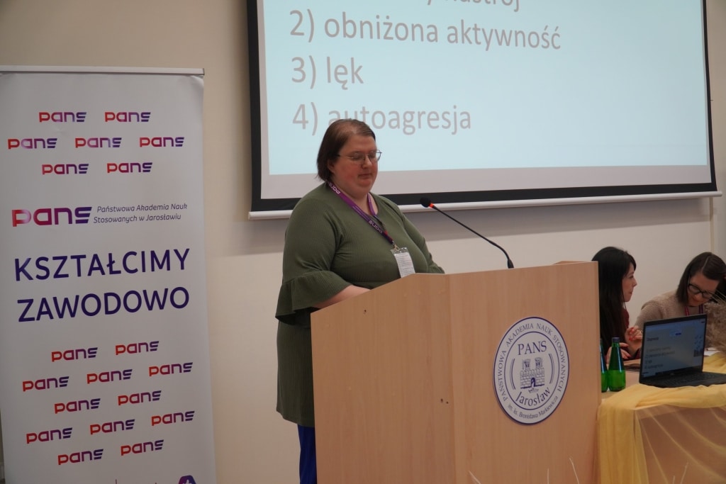 Konferencja naukowa WH: prelegentka przy mównicy z logo PANS Jarosław.