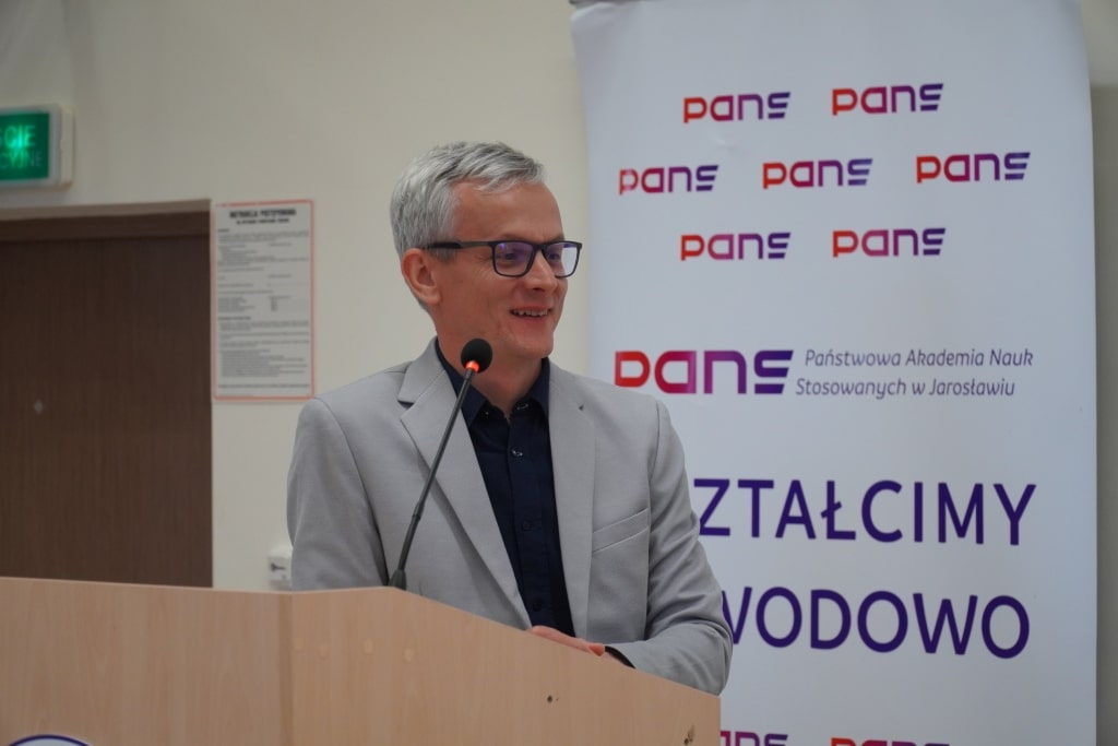 Konferencja naukowa WH: prelegent w szarym garniturze przy mównicy