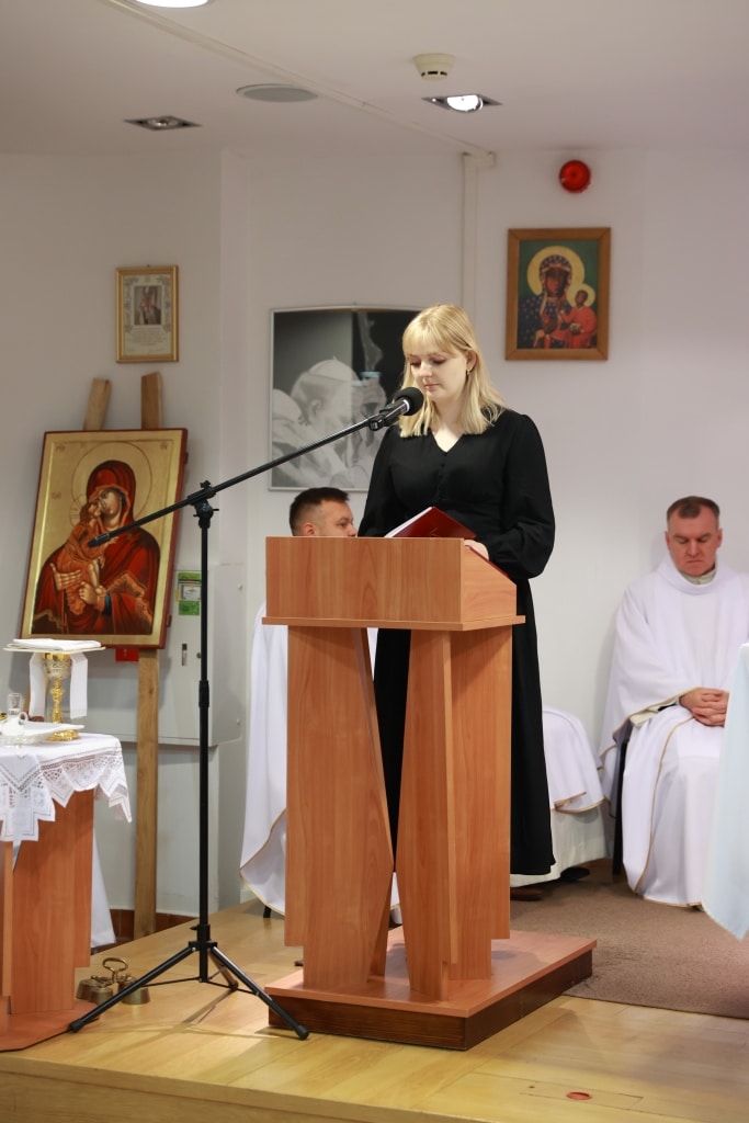Młoda kobieta czyta przy mównicy podczas inauguracji roku akademickiego.