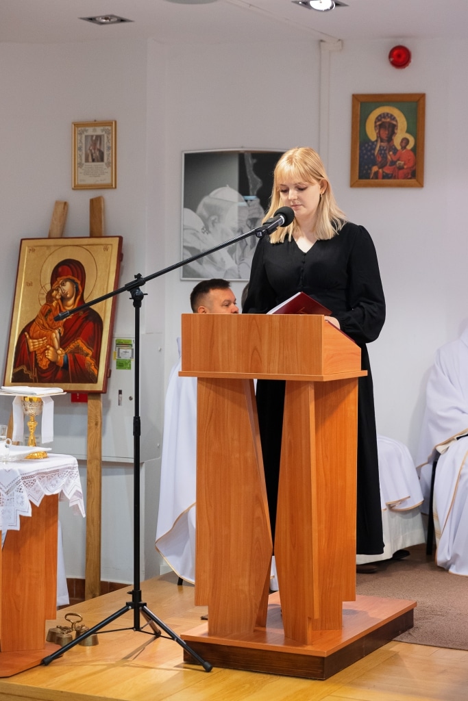 Młoda kobieta czyta tekst z mównicy podczas inauguracji roku akademickiego