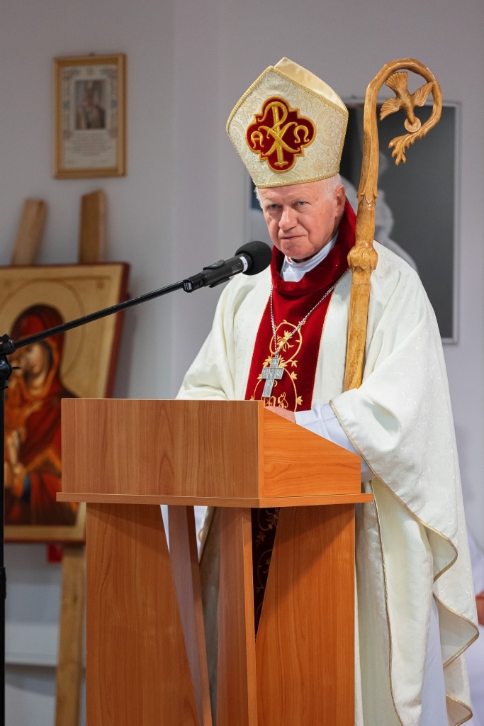 Biskup w szatach liturgicznych przemawia przy pulpicie podczas inauguracji roku akademickiego