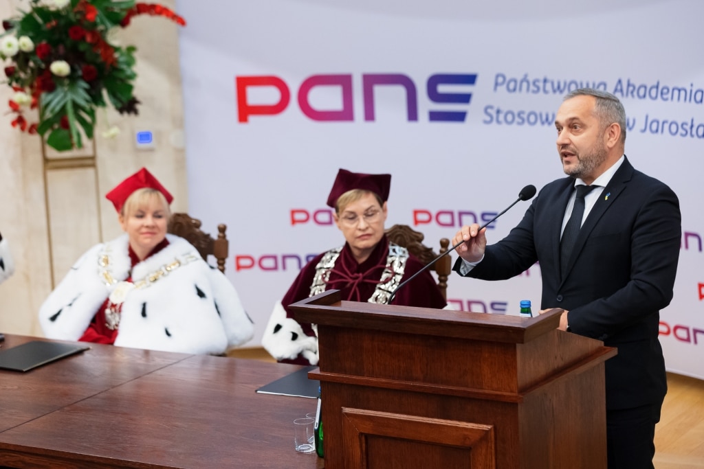 Inauguracja Roku Akademickiego PANS Jarosław: mężczyzna przemawia, kobiety w togach.