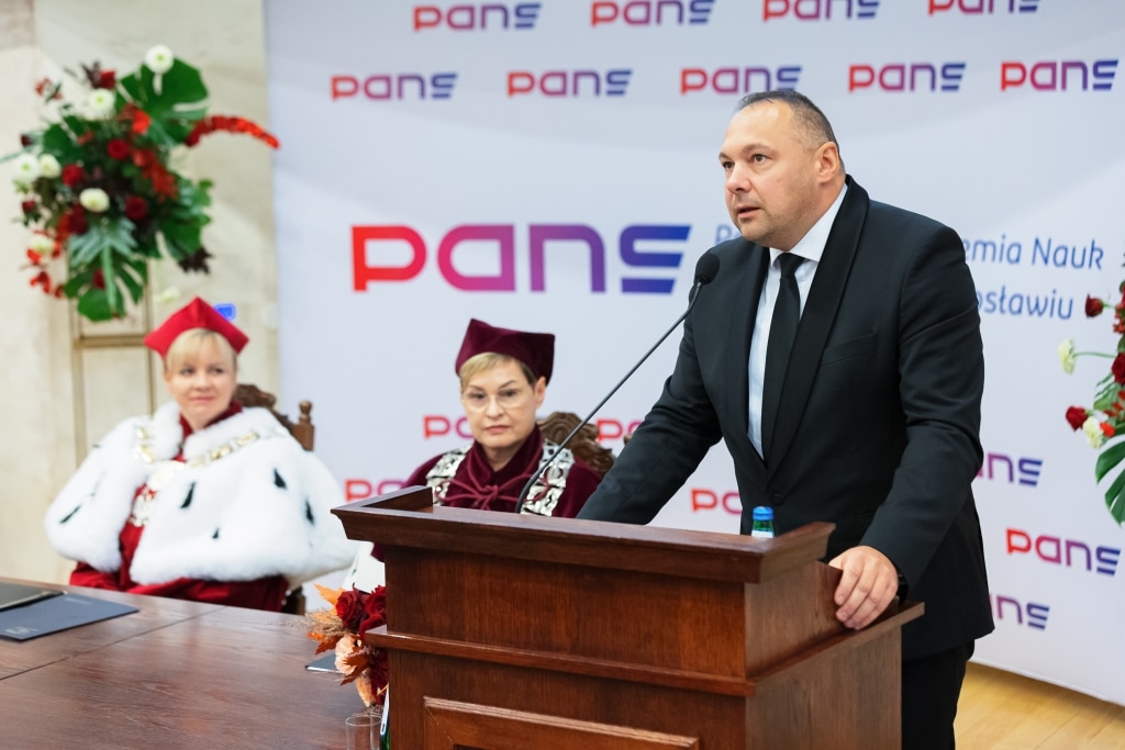 Uroczysta inauguracja roku akademickiego PANS: mężczyzna przemawia, kobiety w togach.