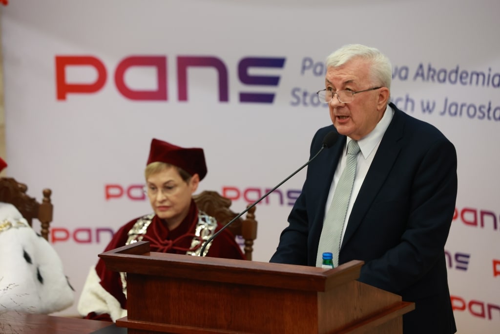 Inauguracja Roku Akademickiego: przemawia mężczyzna w garniturze, obok siedzi kobieta w todze.