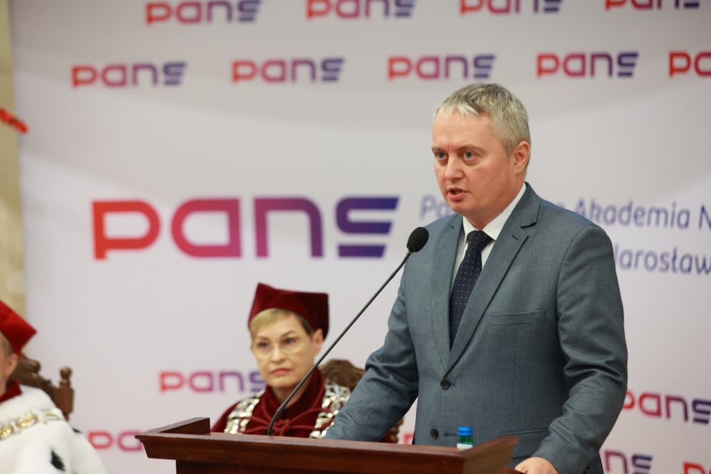 Inauguracja Roku Akademickiego: Mężczyzna przemawia na podium, obok kobieta w todze.