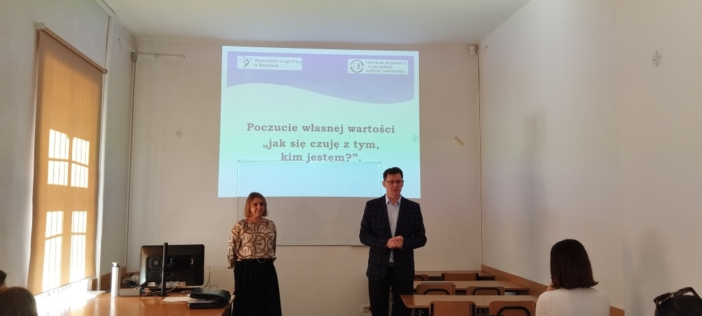Warsztaty z poczucia własnej wartości: prowadzący na tle prezentacji