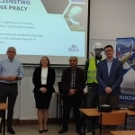 Grupa osób na spotkaniu z firmą budowlaną BESTA, prezentacja o BHP.