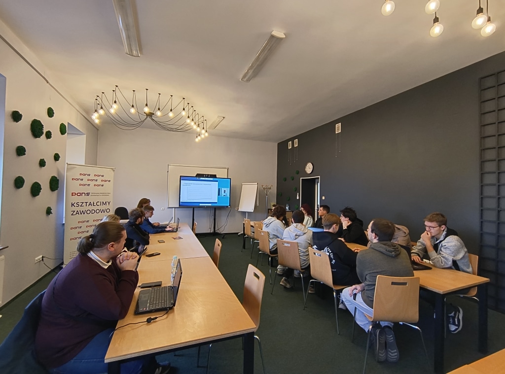 Uczestnicy konferencji RIPE w Jarosławiu siedzą w sali szkoleniowej przy stołach z laptopami.