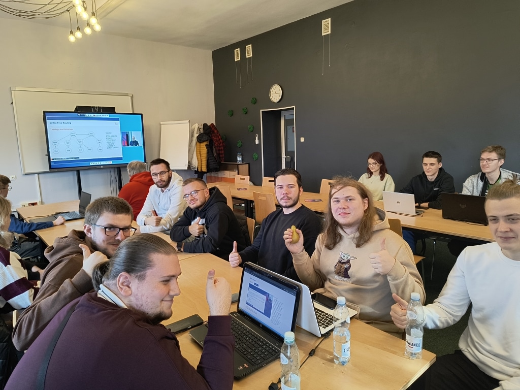 Grupa młodych ludzi na konferencji RIPE w Jarosławiu, pracująca przy laptopach.