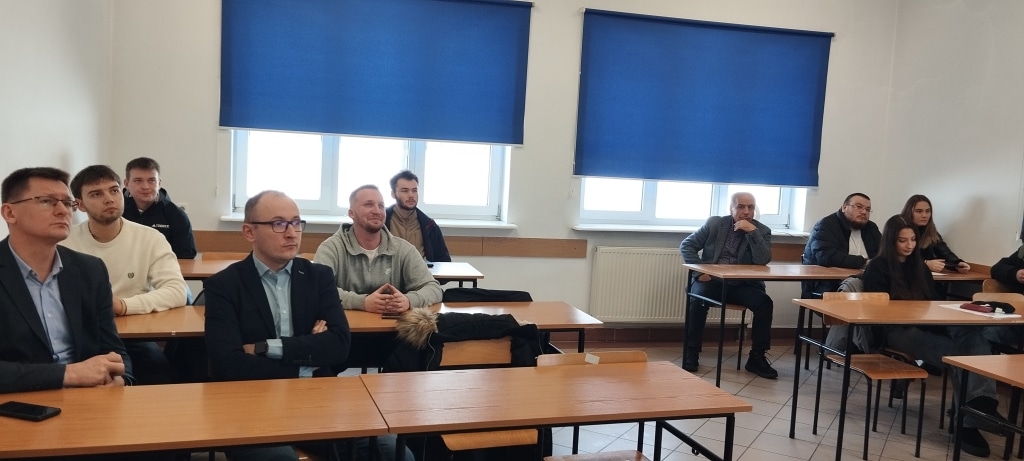 Grupa osób słucha prezentacji podczas spotkania z przedstawicielem MDM Polska.