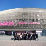 Grupa osób przed TAURON Areną Kraków z napisem "WEJŚCIE 1