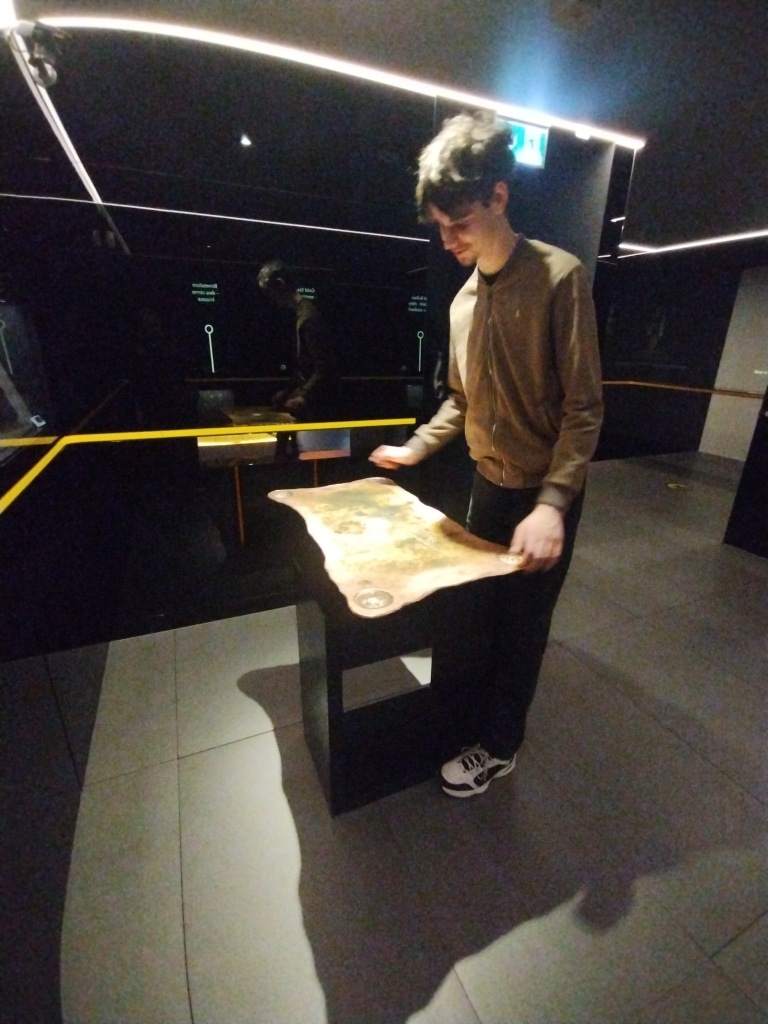 Student na wizycie studyjnej w Centrum Pieniądza NBP ogląda mapę historyczną.