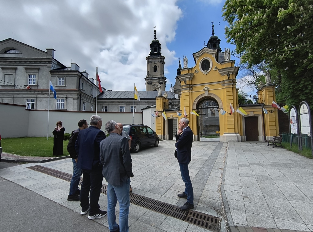 Grupa mężczyzn przed barokową bramą klasztoru w Jarosławiu