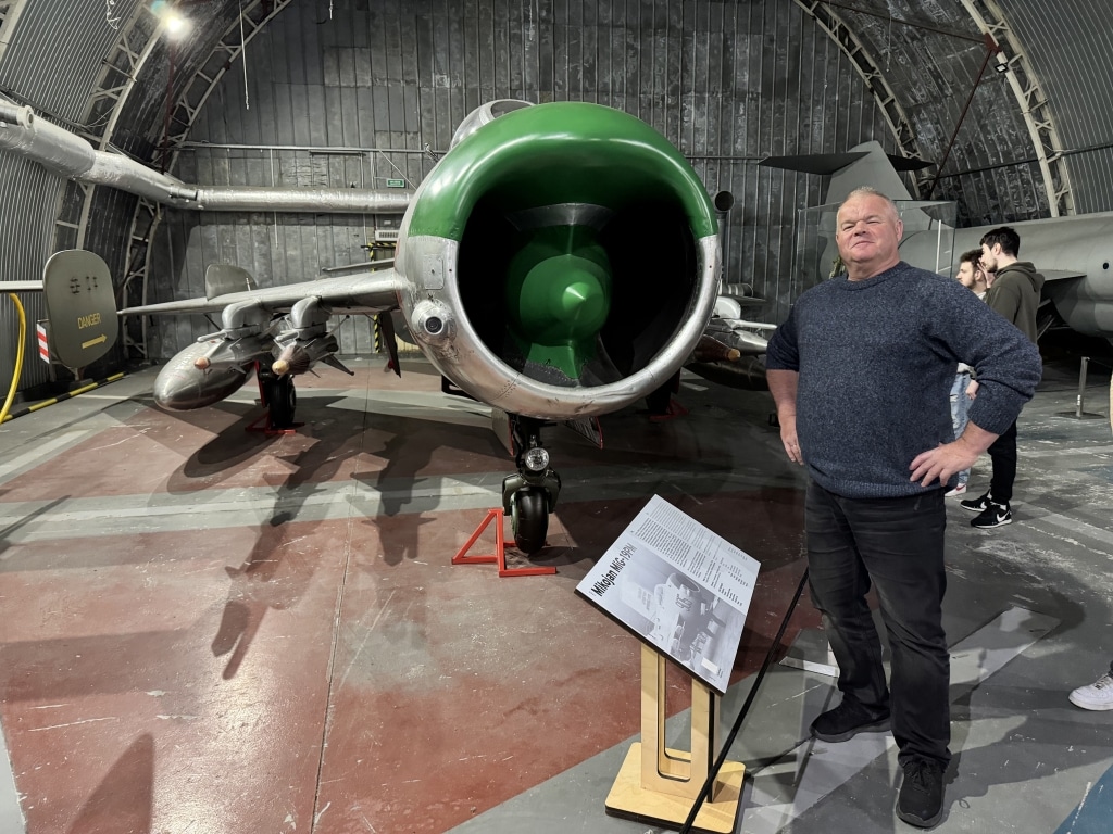 Mężczyzna obok myśliwca MiG-17 w muzeum lotnictwa w Krakowie