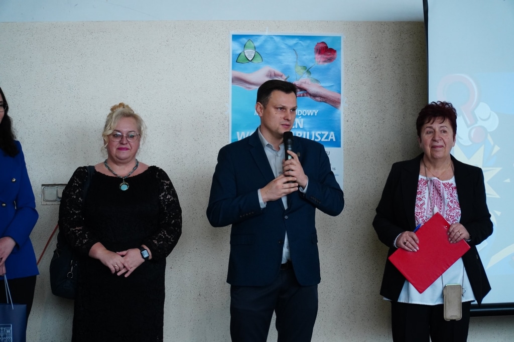 Mężczyzna z mikrofonem podczas gali wolontariatu z dwiema kobietami