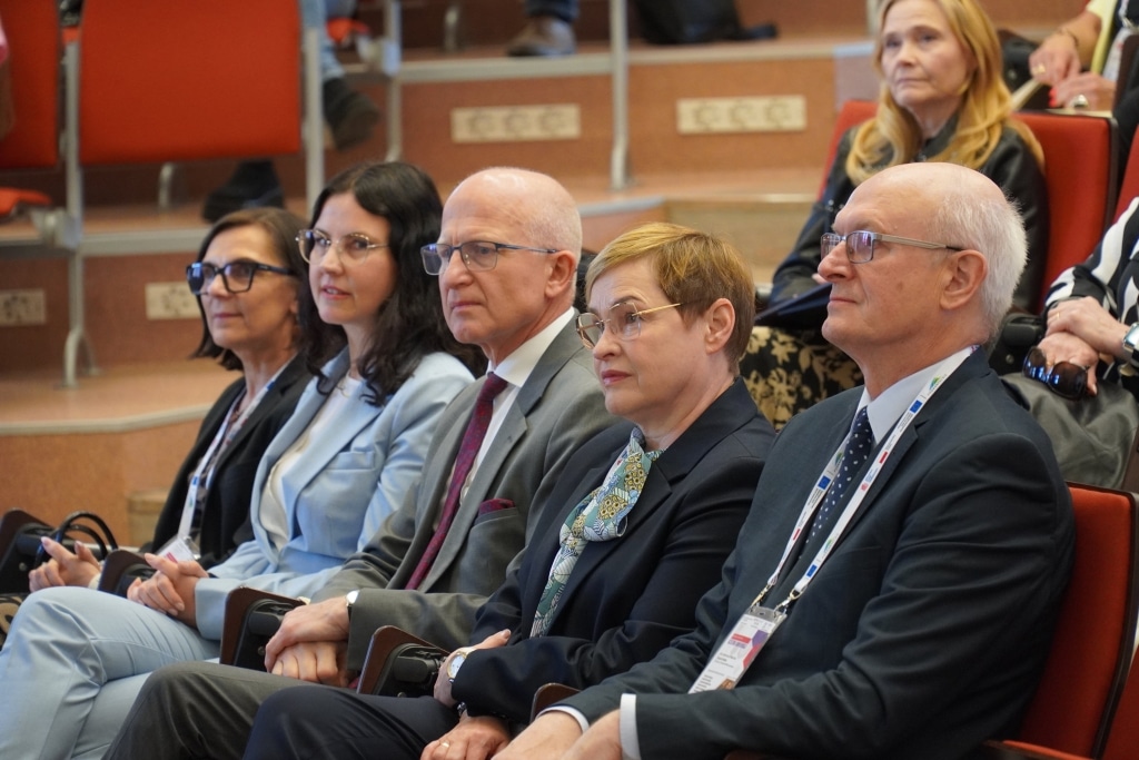 Uczestnicy konferencji „Od szkoły tradycyjnej do szkoły innowacyjnej” siedzą w rzędzie.