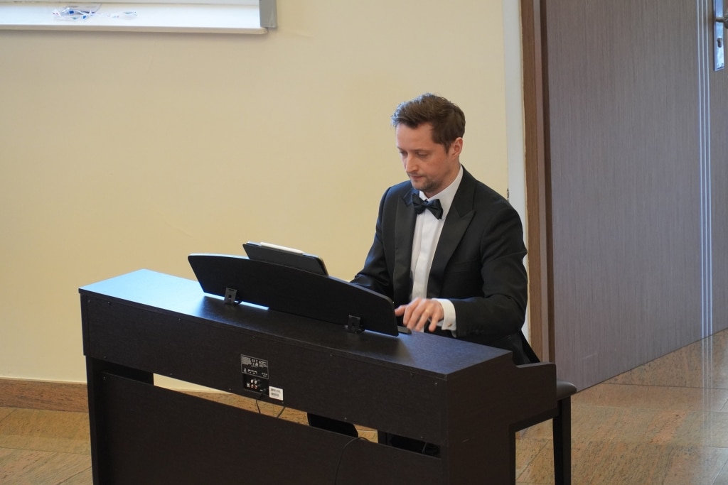 Pianista w czarnym smokingu gra na pianinie cyfrowym podczas konferencji