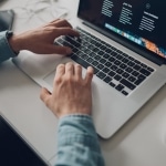 Programista .NET pisze kod na laptopie podczas praktyk.