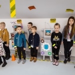 Dzieci stoją obok robotów, przygotowując się do misji ratunkowej.