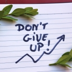 Notatnik z napisem "Don't give up!" i rosnącym wykresem