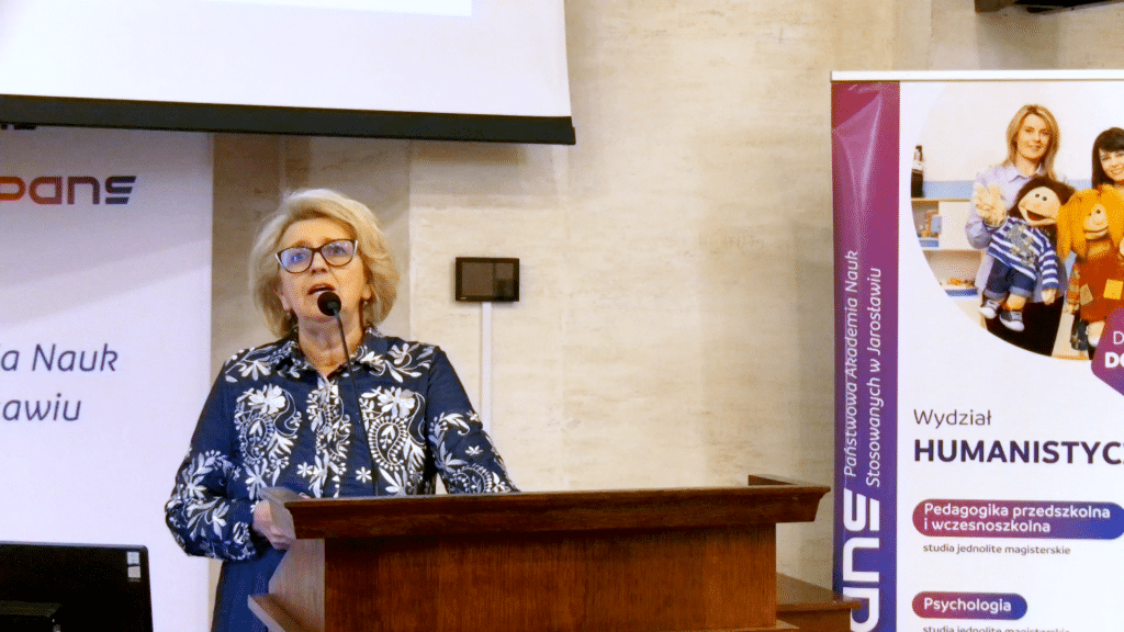 Kobieta w okularach przemawia podczas konferencji dla dyrektorów szkół.