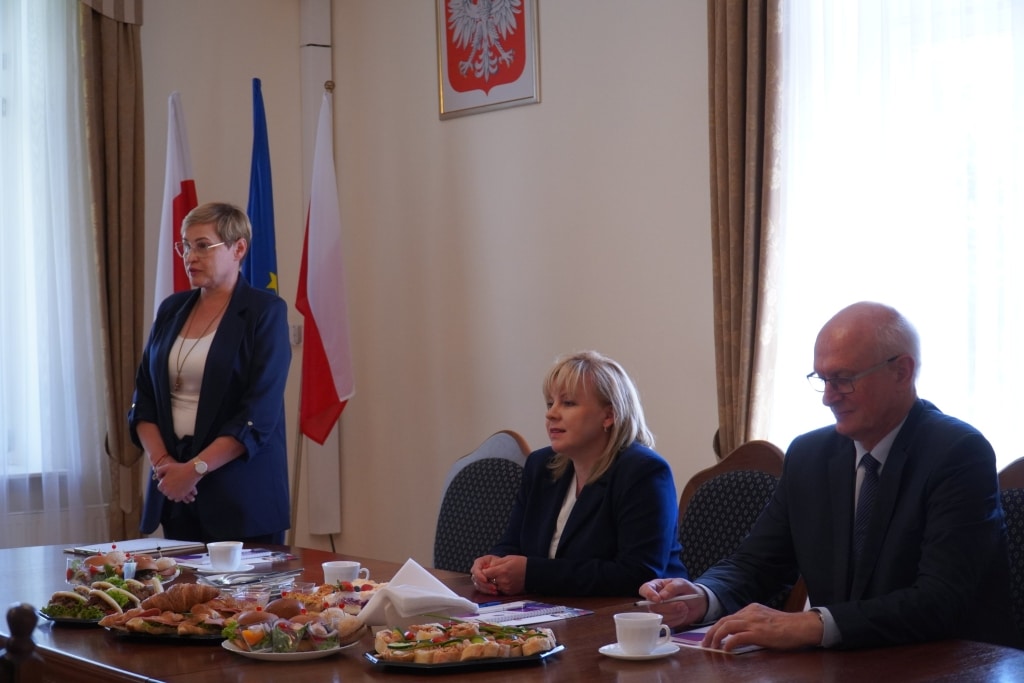 Spotkanie władz uczelni z przedstawicielami oświaty przy stole z przekąskami.