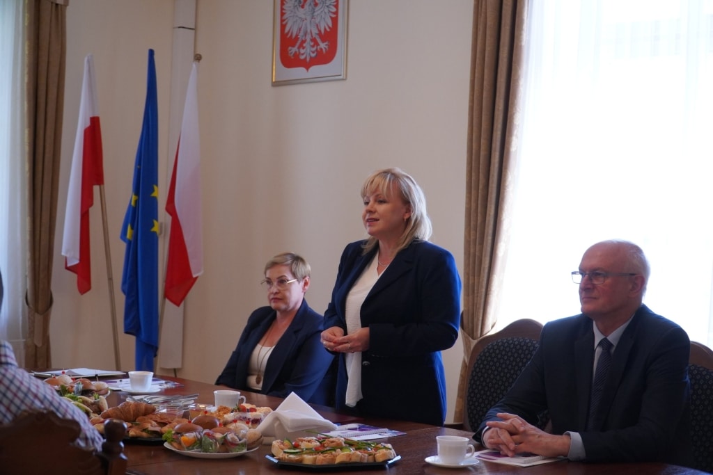 Władze uczelni i przedstawiciele oświaty na spotkaniu w sali konferencyjnej.