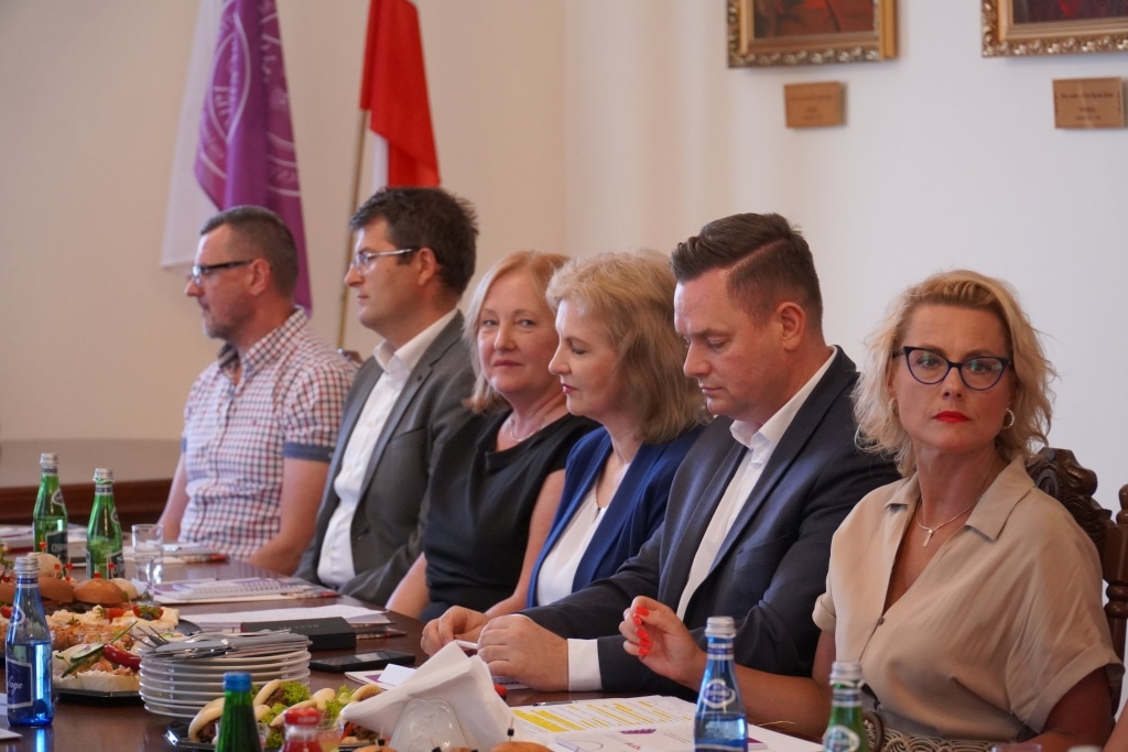 Spotkanie władz uczelni z przedstawicielami placówek oświaty przy stole.