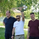 Trzech mężczyzn podczas Święta Uczelni 2026, jeden trzyma trofeum.