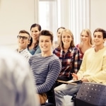 Studenci I roku na dniu adaptacyjnym, uśmiechnięci i słuchający wykładowcy.