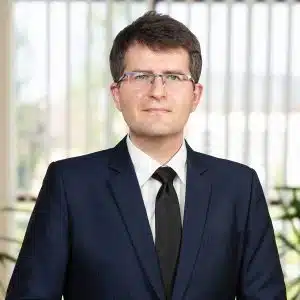 Marek Banaś w garniturze i okularach