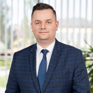Portret biznesowy Jarosława Noworóla w granatowym garniturze w kratę.