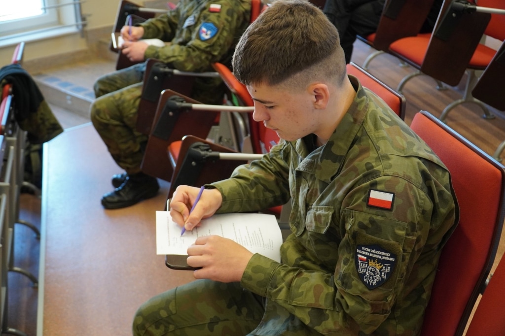 Uczeń w mundurze pisze sprawdzian podczas I Wojewódzkich Zawodów Klas Mundurowych.